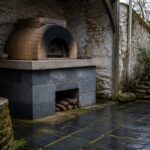Brick pizza oven in an outdoor cooking area beside a work surface
