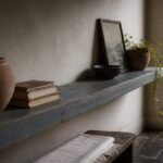 Living room shelf with stacked books a small plant and framed personal objects